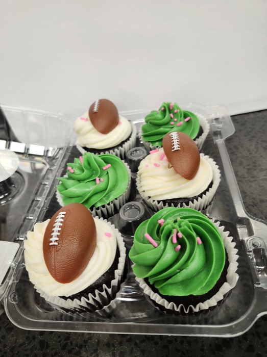 Chocolate cupcakes with green and white frosting topped with chocolate footballs