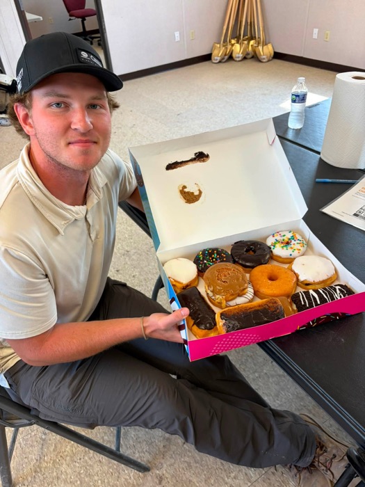 A customer holding open a box of assorted Sweet Street donuts
