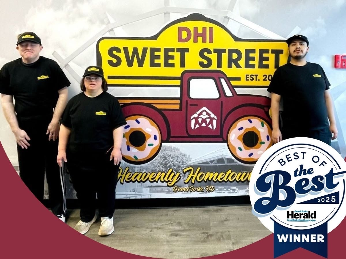 Three DHI Sweet Street team members in black Sweet Street uniforms standing in front of the bakery's food-truck sign, with a Grand Forks Herald Best of the Best 2025 Winner badge